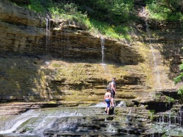 Family exploring a scenic waterfall near Sugar Creek Glen Camping in New York