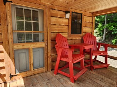 Cabin porch with red chairs at Sugar Creek Glen Camping in New York