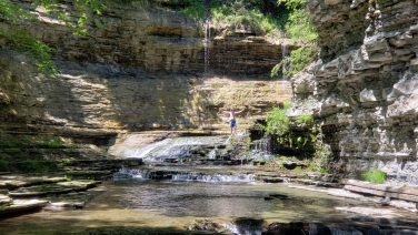 Child exploring a rocky waterfall area near Sugar Creek Glen Camping in New York