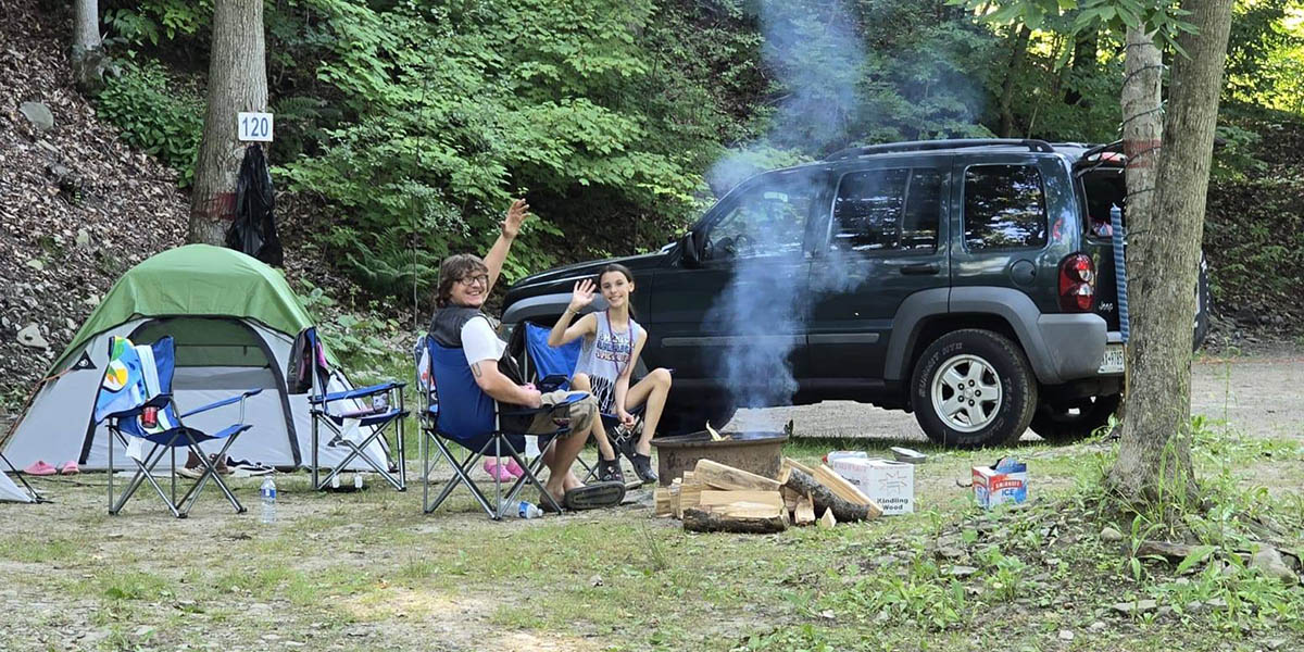Couple relaxing around a campfire at their campsite during a weekend getaway at Sugar Creek Glen Campground