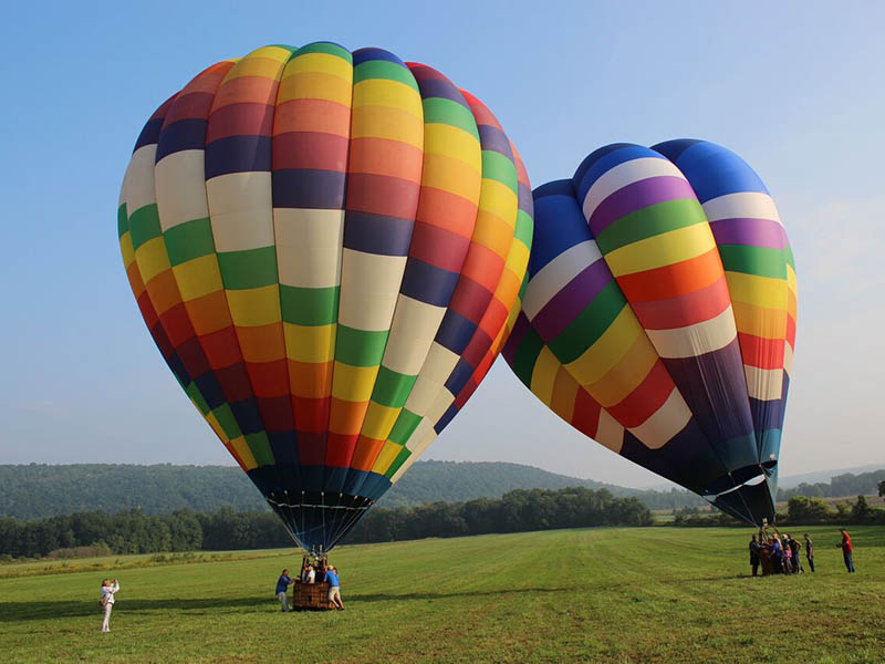 Two colorful hot air balloons preparing for flight in a grassy field near Dansville, New York.